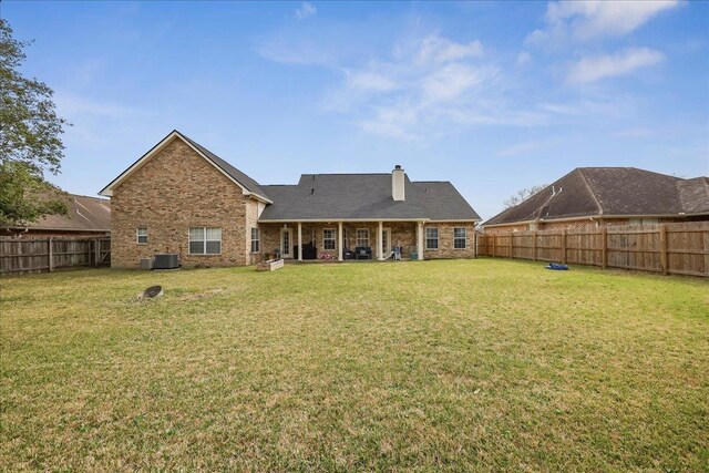 back of house featuring a fenced backyard, a lawn, and brick siding