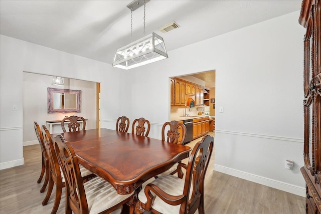 dining room with light wood finished floors, visible vents, and baseboards