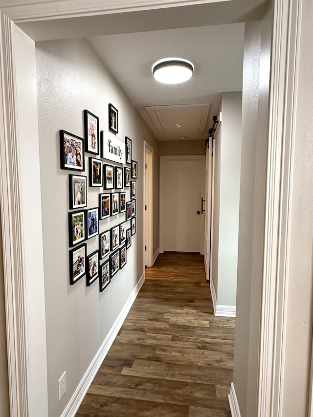 corridor with dark wood-type flooring, attic access, and baseboards