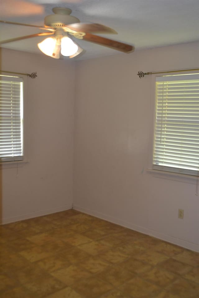 empty room with ceiling fan and a wealth of natural light