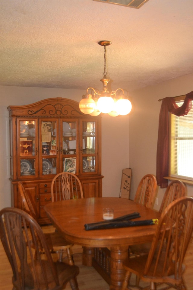 dining area with hardwood / wood-style flooring, a textured ceiling, and an inviting chandelier