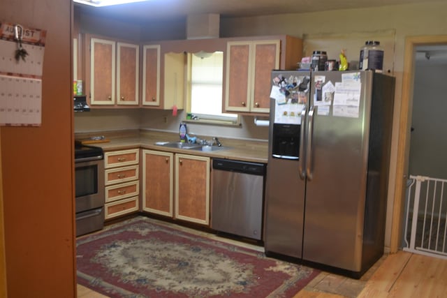 kitchen with appliances with stainless steel finishes, light wood-type flooring, and sink