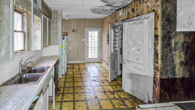 kitchen with white cabinetry, sink, tile countertops, and backsplash