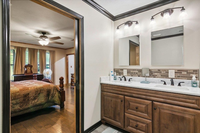 bathroom with tasteful backsplash, vanity, ceiling fan, crown molding, and wood-type flooring