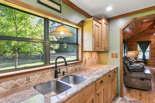 kitchen with a wealth of natural light, decorative backsplash, sink, and light stone counters