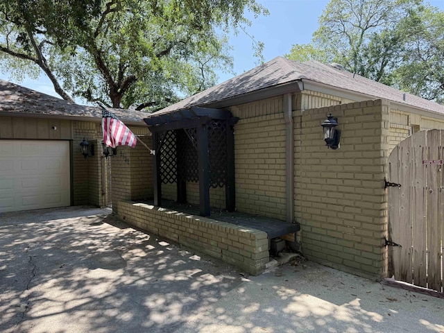 5835 Calder Ave, Beaumont, TX 77706 - view of side of home with brick siding, roof with shingles, a garage, driveway, and a gate