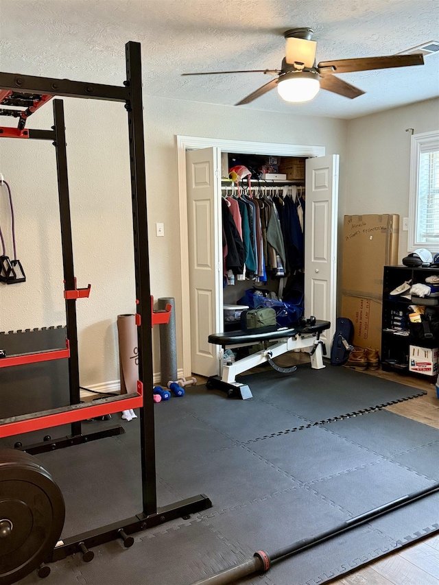 exercise room featuring visible vents, a textured ceiling, and a ceiling fan