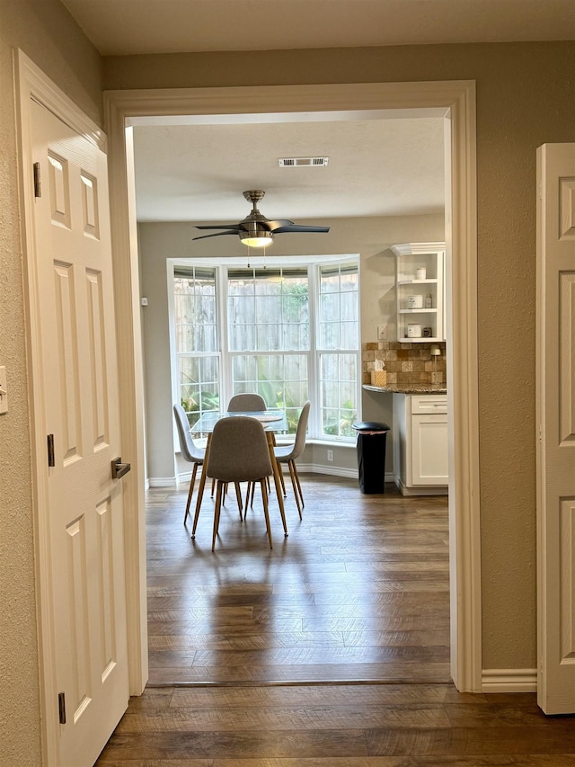 dining area featuring dark wood finished floors, visible vents, ceiling fan, and baseboards