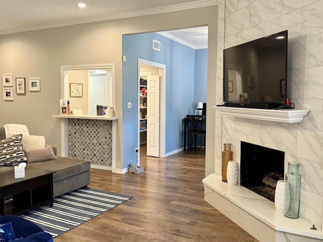 living area with wood finished floors, visible vents, baseboards, a fireplace, and ornamental molding