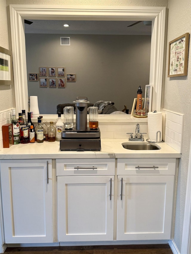 bar with indoor wet bar, visible vents, and a sink