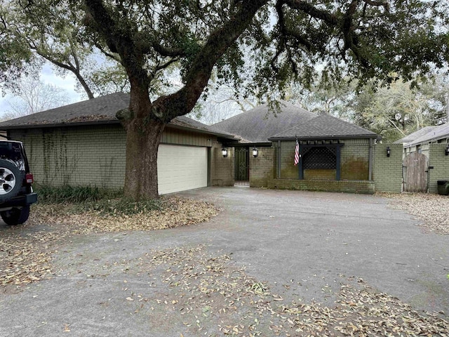 view of front of house featuring aphalt driveway, brick siding, roof with shingles, and an attached garage