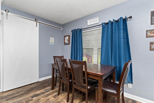 dining room featuring a barn door, baseboards, a textured ceiling, and dark wood finished floors