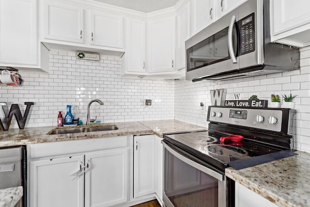 kitchen with white cabinets, light stone countertops, stainless steel appliances, and a sink