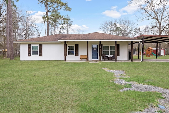 ranch-style house featuring stucco siding, a front lawn, a playground, a shingled roof, and a carport