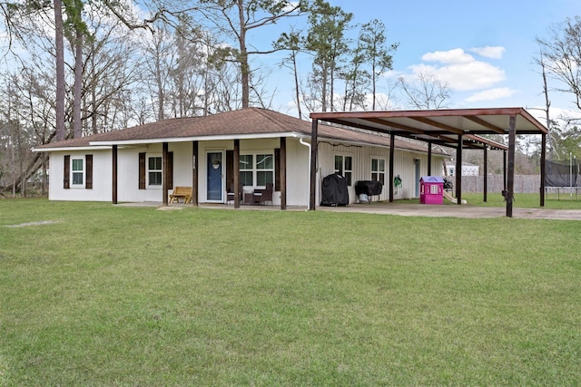 exterior space featuring driveway, roof with shingles, a yard, a carport, and a trampoline