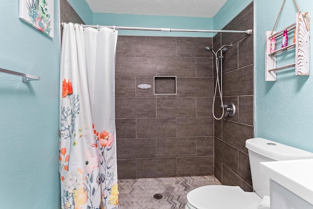 full bathroom featuring vanity, toilet, a stall shower, and a textured ceiling