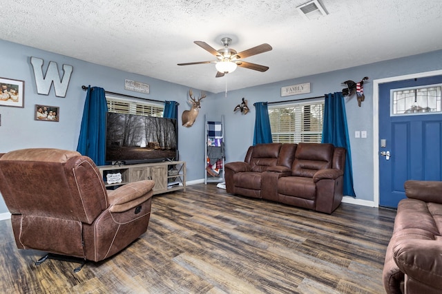 living area with visible vents, a textured ceiling, baseboards, and wood finished floors