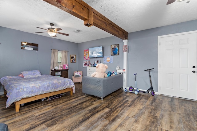 bedroom featuring beamed ceiling, a textured ceiling, wood finished floors, baseboards, and ceiling fan