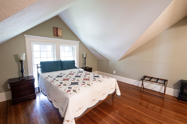 bedroom with a textured ceiling, dark wood-type flooring, and vaulted ceiling