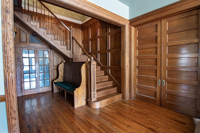 entryway featuring wood-type flooring, french doors, and wood walls