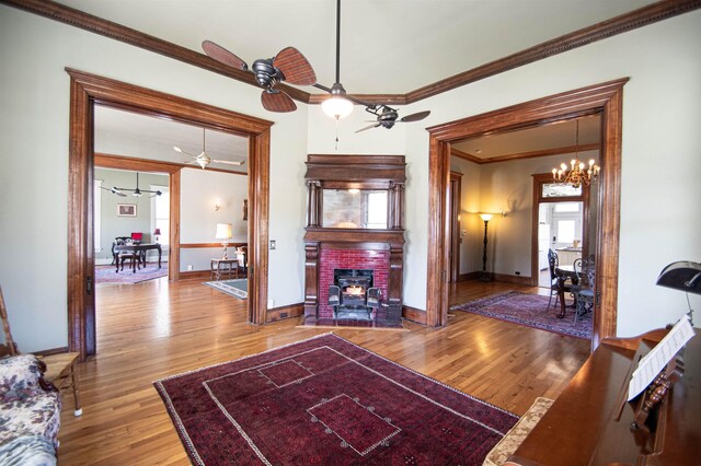 2108 Harrison Ave, Beaumont, TX 77701 - living area featuring ornamental molding, wood finished floors, ceiling fan, a brick fireplace, and a chandelier