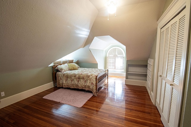 bedroom featuring vaulted ceiling, dark wood-type flooring, and a closet