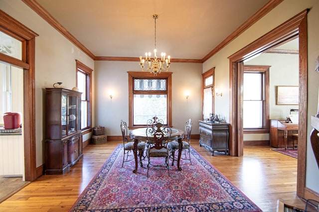 dining space with ornamental molding, light hardwood / wood-style flooring, and a notable chandelier