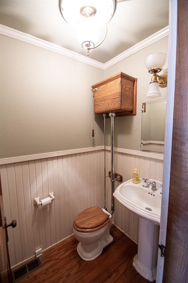 bathroom with hardwood / wood-style flooring, toilet, and ornamental molding