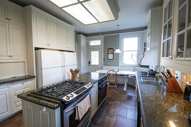 2108 Harrison Ave, Beaumont, TX 77701 - kitchen with stainless steel gas range, freestanding refrigerator, glass insert cabinets, white cabinets, and decorative light fixtures