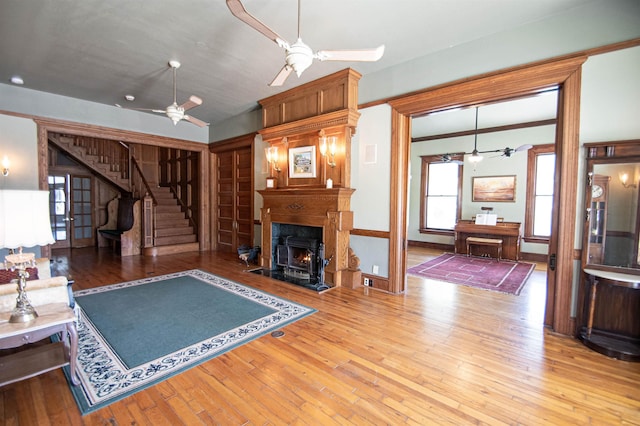 living room with wood-type flooring, a wood stove, ceiling fan, and lofted ceiling