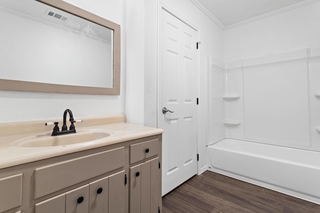 bathroom with washtub / shower combination, vanity, wood-type flooring, and ornamental molding