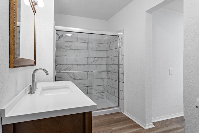 bathroom with hardwood / wood-style flooring, vanity, a textured ceiling, and walk in shower