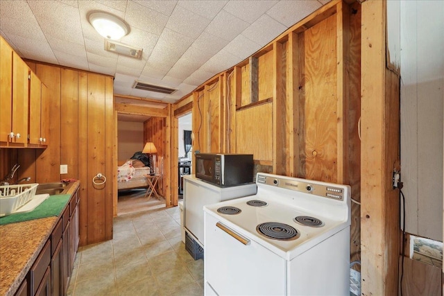 2432 Wespine Dr, Beaumont, TX 77707 - kitchen featuring electric range, black microwave, wood walls, brown cabinetry, and a sink