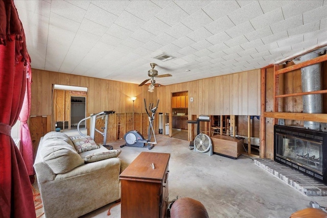 2432 Wespine Dr, Beaumont, TX 77707 - living room featuring wooden walls, concrete floors, a fireplace, and a ceiling fan