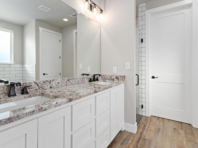 bathroom featuring a sink, visible vents, wood finished floors, and double vanity
