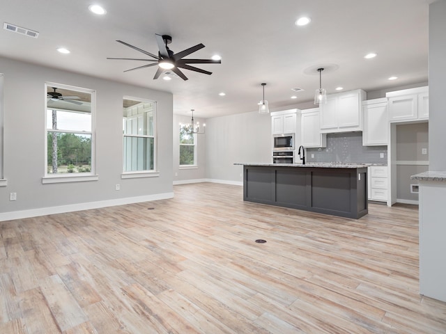kitchen with visible vents, a sink, appliances with stainless steel finishes, white cabinetry, and a wealth of natural light