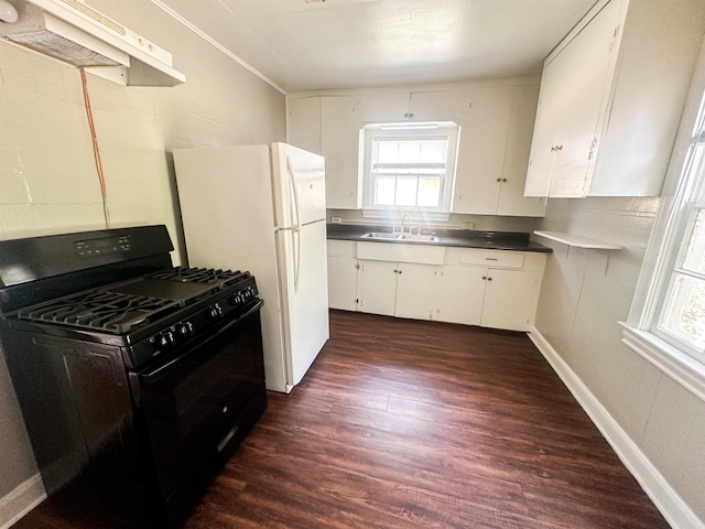 5070 Wilshire Dr, Beaumont, TX 77703 - kitchen featuring black range with gas cooktop, under cabinet range hood, dark wood-style flooring, white cabinets, and freestanding refrigerator