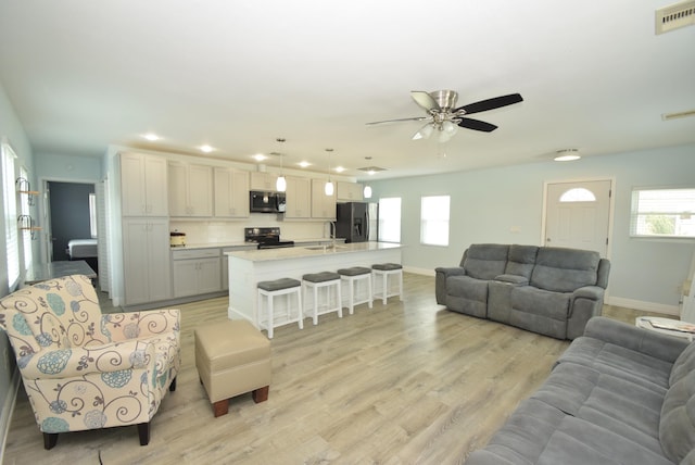 living room with light hardwood / wood-style flooring, ceiling fan, and sink