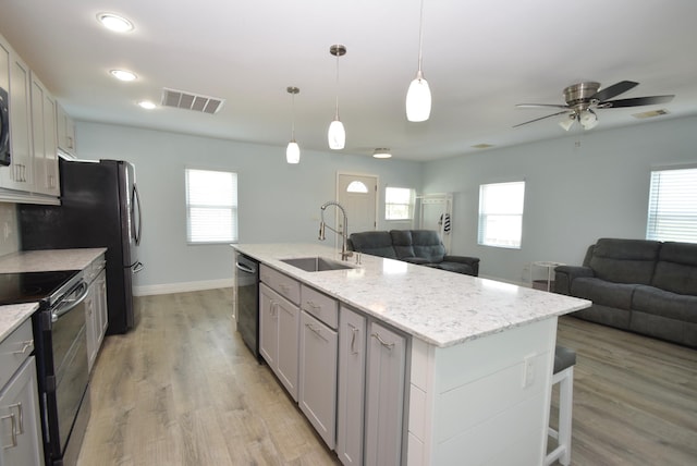 kitchen with dishwasher, a center island with sink, hanging light fixtures, sink, and black range with electric cooktop