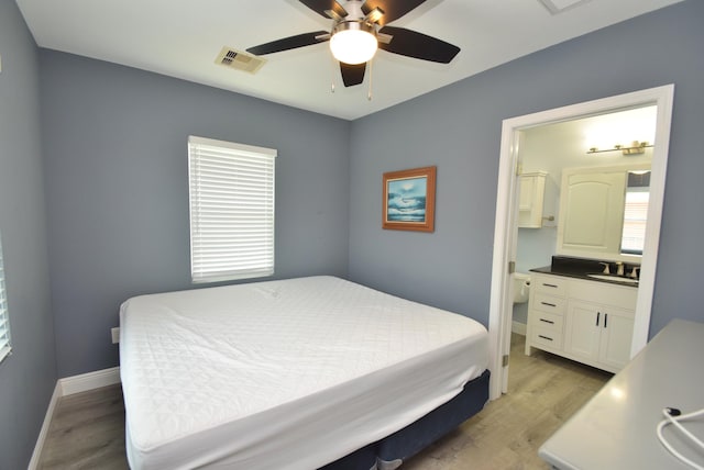 bedroom featuring light wood-type flooring, ensuite bath, and ceiling fan