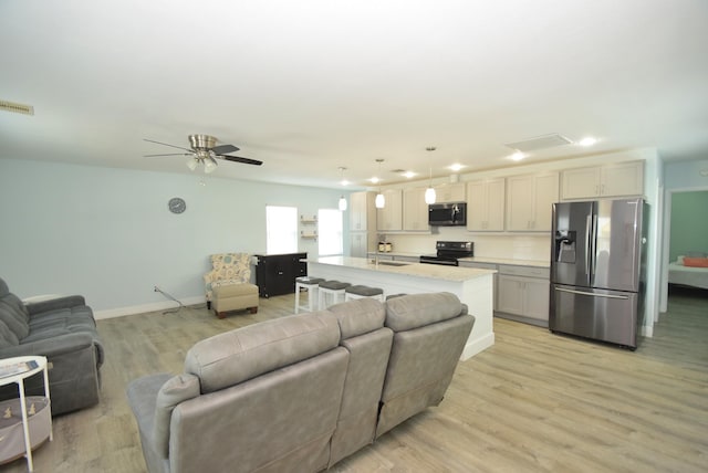 living room with ceiling fan, sink, and light wood-type flooring