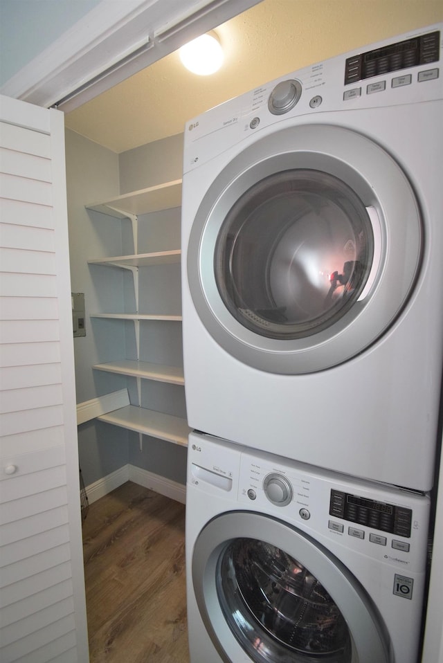 laundry area with dark hardwood / wood-style floors and stacked washer / dryer