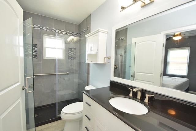 bathroom featuring vanity, ceiling fan, toilet, and a shower with door