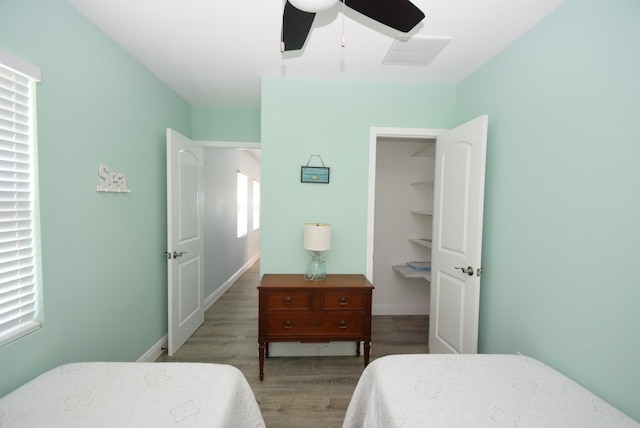 bedroom featuring ceiling fan, a walk in closet, and light hardwood / wood-style flooring