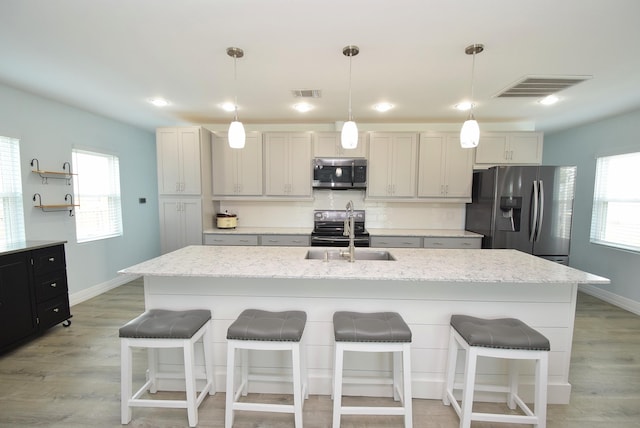 kitchen with sink, an island with sink, and stainless steel appliances