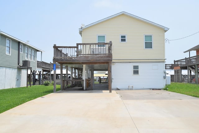 back of property with a yard, a deck, and a carport