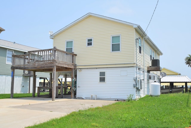 back of property featuring a deck, a carport, a lawn, and central air condition unit