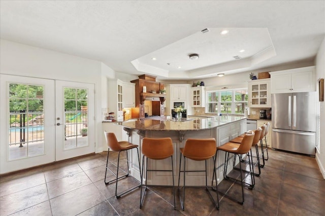 8185 Dawn Dr, Beaumont, TX 77705 - kitchen with freestanding refrigerator, french doors, a raised ceiling, a spacious island, and white cabinets