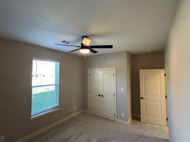 unfurnished bedroom featuring a closet, light colored carpet, and ceiling fan