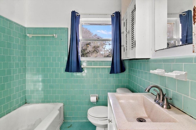 bathroom featuring a washtub, vanity, toilet, and tile walls